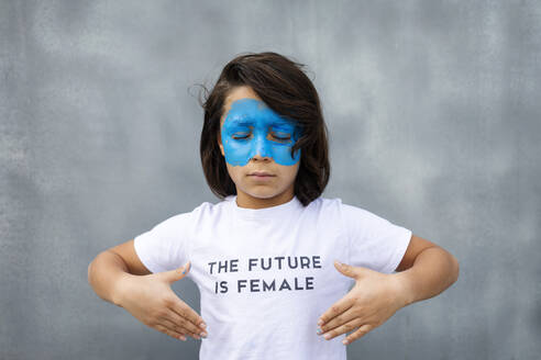 Porträt eines Jungen mit aufgemalter blauer Maske im Gesicht, der ein T-Shirt mit dem Aufdruck 'The Future is Female' trägt - VABF02930