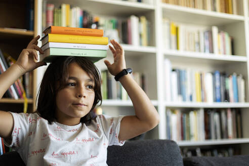 Porträt eines Jungen, der einen Stapel Bücher auf seinem Kopf balanciert - VABF02946