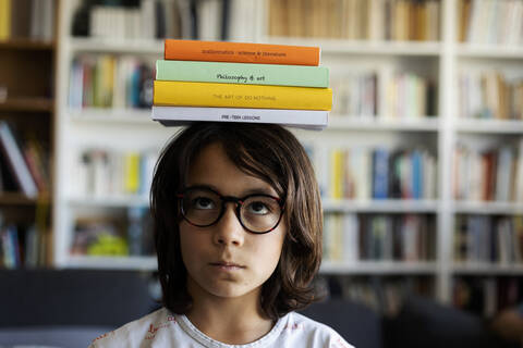 Portrait of boy balancing stack of books on his head stock photo