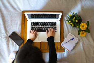 Overhead view of a woman working in bed with the computer. - CAVF80847