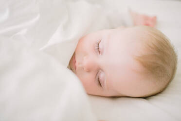 Peaceful and ethereal sleeping baby surrounded in white blanket - CAVF80876