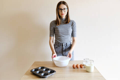 Frau in T-Shirt und Jeans bereitet in ihrer Küche hausgemachte Cupcakes zu, lizenzfreies Stockfoto