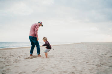 Father and child son playing a the beach on a cloudy day - CAVF80997