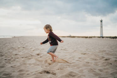 Kind Junge Kind spielt am Strand an einem bewölkten Tag - CAVF81002