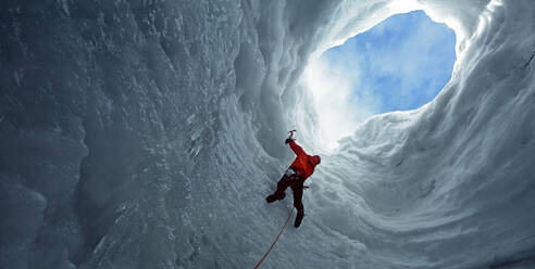 Mann klettert zu einer Öffnung in einer Eishöhle am Langjokull-Gletscher - CAVF81007