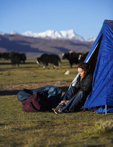 Frau beim Anziehen ihrer Stiefel in einem Lager in Tibet, lizenzfreies Stockfoto