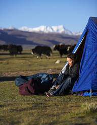 Frau beim Anziehen ihrer Stiefel in einem Lager in Tibet - CAVF81035