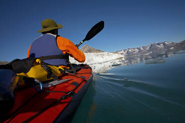 Mann, der mit einem Seekajak durch die Fjorde Ostgrönlands fährt - CAVF81037