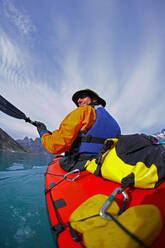 Mann, der mit einem Seekajak durch die Fjorde Ostgrönlands fährt - CAVF81042