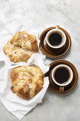 Zwei Tassen schwarzen Kaffee und zwei Brötchen mit gerösteten Mandeln. - CUF55124