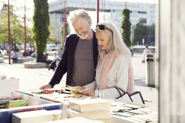 Ein Paar, das sich an einem Marktstand Bücher ansieht. - CUF55193
