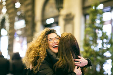 Zwei Frauen lächeln und umarmen sich auf einer Straße in Florenz. - CUF55225