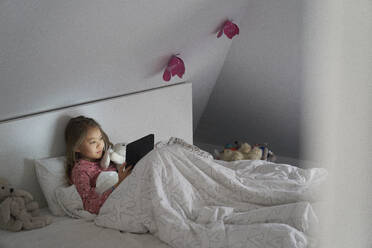 Das Leben zu Hause, ein Schulmorgen während des Einschlusses: Ein Mädchen liegt im Bett und benutzt ein digitales Tablet. - CUF55233