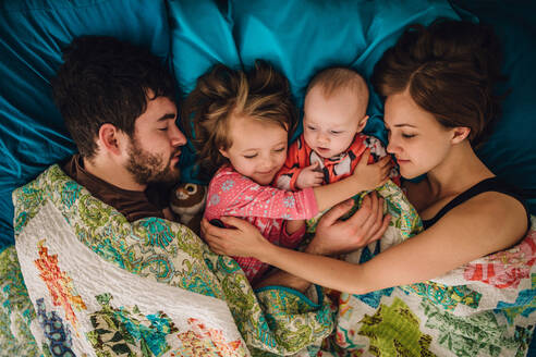 Mama, Papa und Kinder schlafen und umarmen sich morgens im Bett - CAVF81055