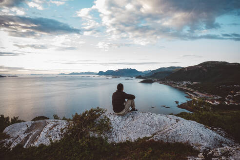 Hiker sitting on a rock looking at sea and islands - CAVF81073