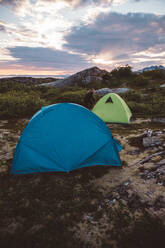 Camper öffnet Zelt bei bewölktem Sonnenuntergang - CAVF81079
