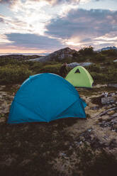 Camper opening tent in cloudy sunset - CAVF81079