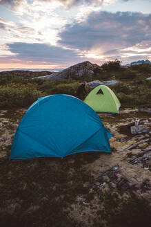 Camper öffnet Zelt bei bewölktem Sonnenuntergang - CAVF81079