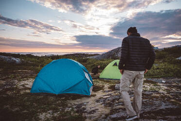 2 Männer auf einem Campingplatz bei Sonnenuntergang und bewölktem Himmel - CAVF81080