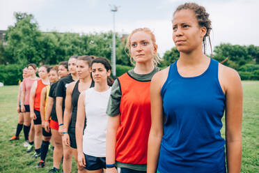 Eine Reihe von Frauen in Sportwesten auf einem Trainingsplatz beim Rugbytraining. - CUF55426