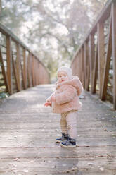 Baby steht auf einer Brücke und schaut in die Kamera - CAVF81112