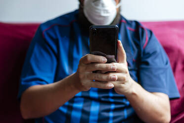 Close-up of a person using his smartphone in quarantine - CAVF81122