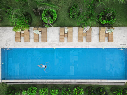 Aerial view of attractive woman floating over water at resort - CAVF81156