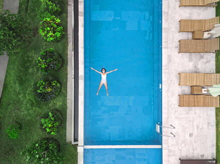Aerial view of attractive woman floating over water at resort - CAVF81158