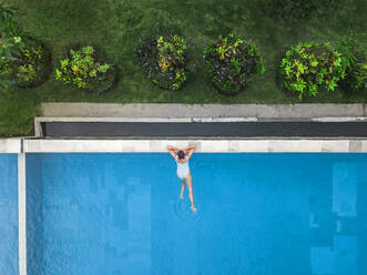 Aerial view of attractive woman floating over water at resort - CAVF81160