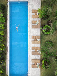Luftaufnahme einer attraktiven Frau, die am Urlaubsort über dem Wasser schwebt - CAVF81162