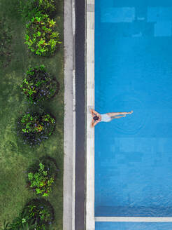 Aerial view of attractive woman floating over water at resort - CAVF81164