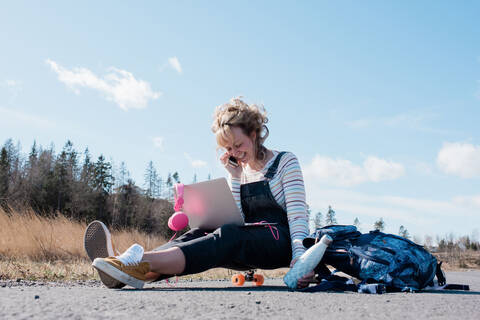 Frau, die beim Skaten telefoniert und an ihrem Laptop arbeitet, lizenzfreies Stockfoto