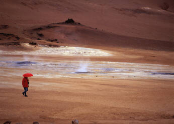 Frau mit rotem Regenschirm in Namskard, einem geothermischen Gebiet mit heißen Quellen - CAVF81289