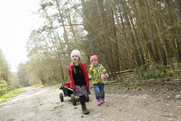 Two little sisters pulling trolley on forest track - BRF01451