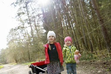 Zwei kleine Schwestern ziehen eine Draisine auf einem Waldweg - BRF01452