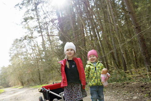 Zwei kleine Schwestern ziehen eine Draisine auf einem Waldweg - BRF01452