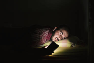 Man lying in bed using smartphone at night - XLGF00171