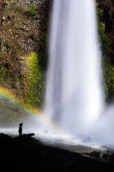 Silhouette einer Person an einem Wasserfall mit einem Regenbogen - CAVF81321