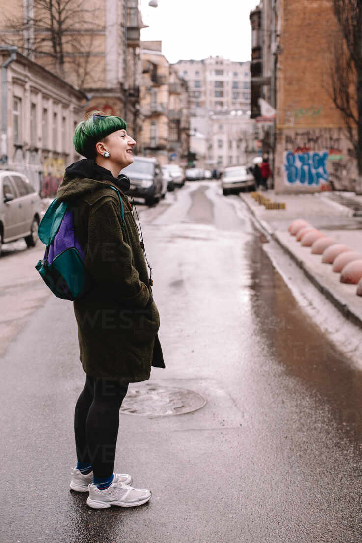 Happy non-binary female hipster standing on the road in city stock photo
