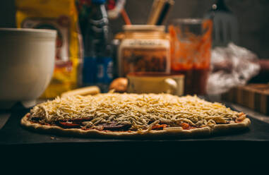 Nahaufnahme der Hand eines Bäckers in weißer Uniform beim Pizzabacken in der Küche - CAVF81402