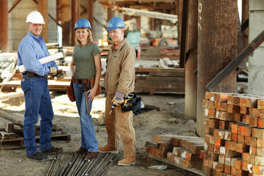 Gruppe von Bauarbeitern, die auf einer Baustelle in die Kamera schauen - CAVF81427