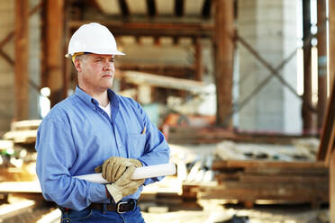 Male construction foreman holding plans looking off camera - CAVF81429