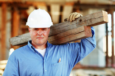 Male construction foreman holding lumber looking at camera - CAVF81431