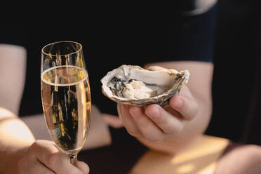 Eine Auster und ein Glas Champagner in der Hand - CAVF81516