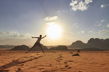 Frau, die in der Wüste von Wadi Rum, Jordanien, über den roten Sand springt - VEGF02282