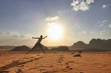 Woman jumping on the red sand desert in Wadi Rum desert, Jordan - VEGF02282