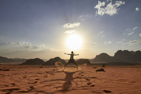 Frau, die in der Wüste von Wadi Rum, Jordanien, über den roten Sand springt - VEGF02284