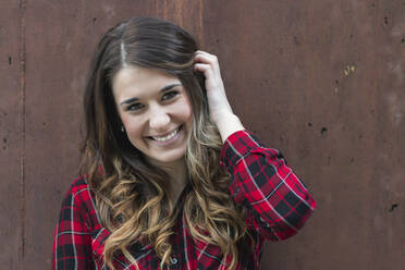 Portrait of smiling young woman wearing red plaid shirt - MTBF00405