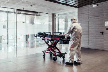 Ambulance, doctor wearing protective suit pushing empty stretcher - JAF00002