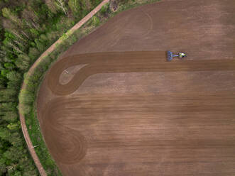Russia, Moscow region, Aerial view of tractor on agricultural field and trees - KNTF04608